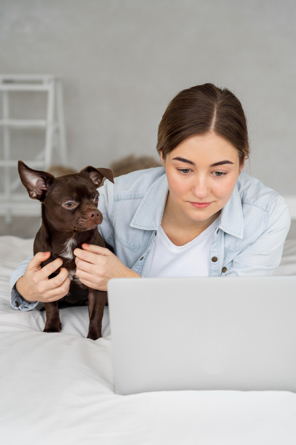 girl in bed with laptop and dog